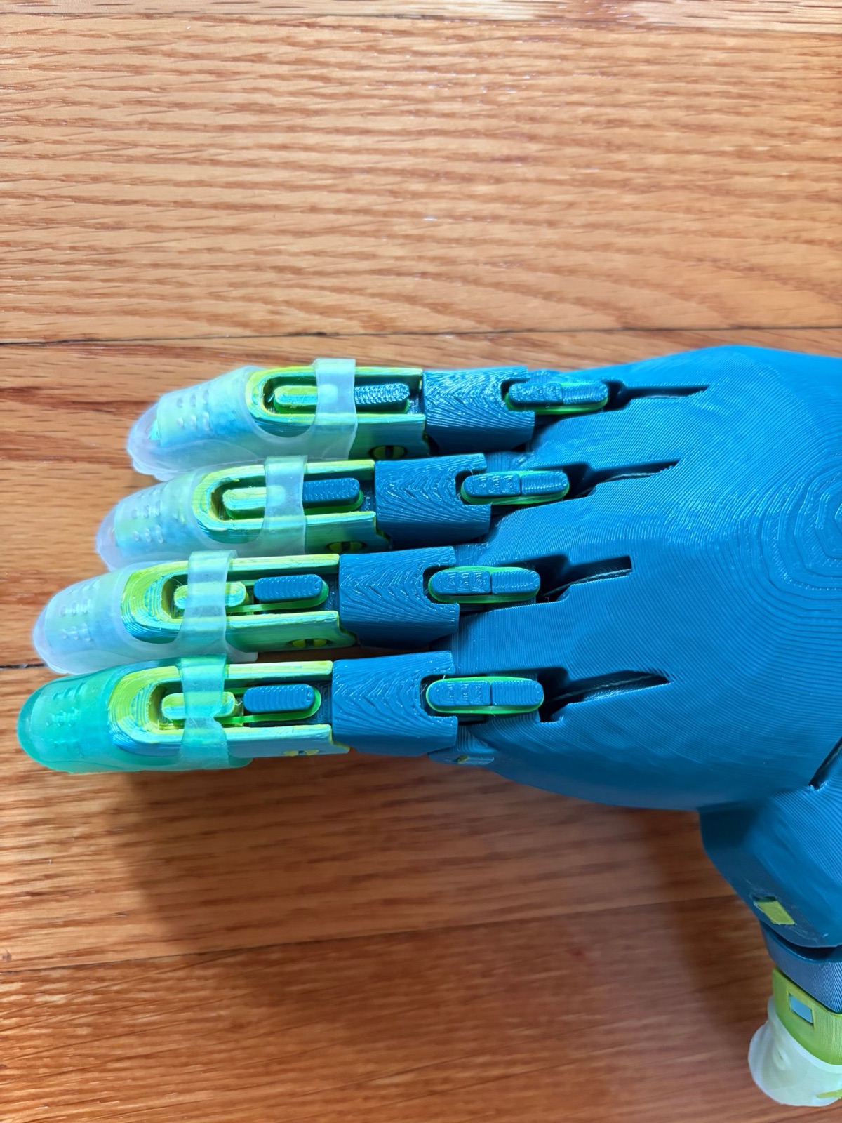 Close-up of teal fingers with lime-green joints and clear gecko-grip fingertips
