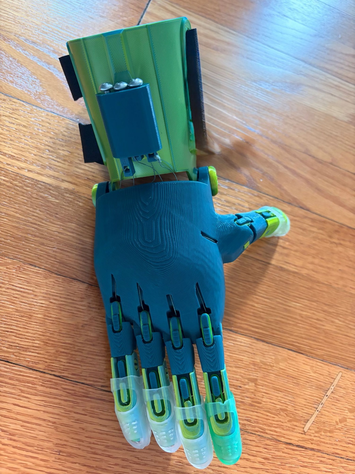 A teal and lime-green hand with its wrist gauntlet, seen from the back